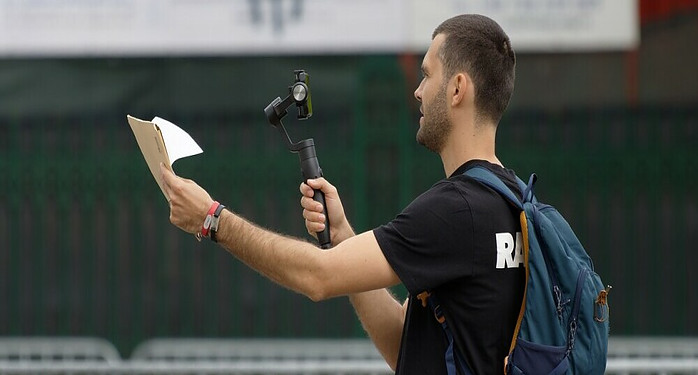 a man holding a script and camera while he creates a vlog