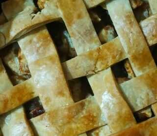 two apples sitting beside a delicious perfectly baked apple pie