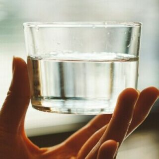 water in a glass being held up to symbolize hydration